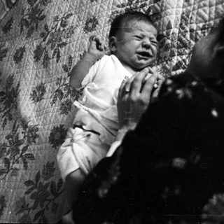 A crying infant in distressed indoor setting.