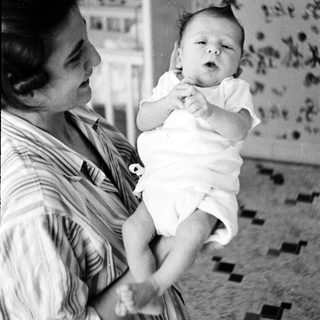 A woman holding an infant indoors.
