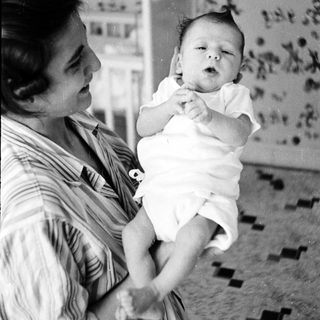 A woman holding an infant indoors.
