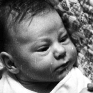 Infant sleeping peacefully on patterned blanket.