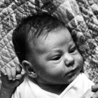 Infant sleeping peacefully on patterned blanket.