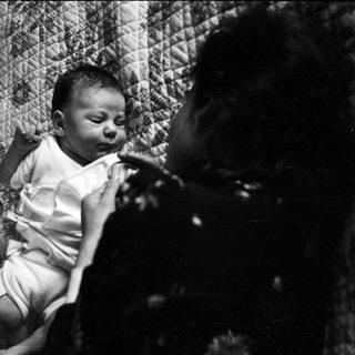 Infant lying on woven mat.