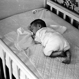 Infant sleeping in worn crib.
