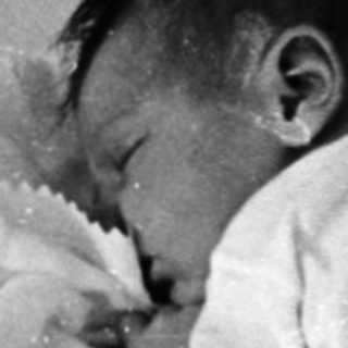 Infant sleeping in worn crib.