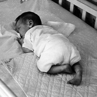 Infant sleeping in worn crib.