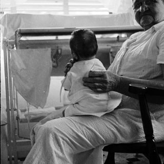 A man holds a baby in a hospital setting.