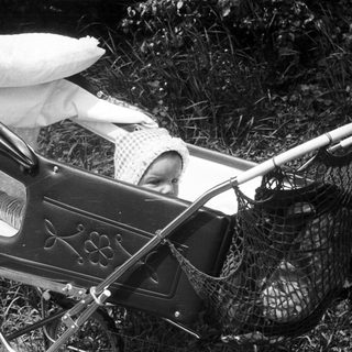 Baby in vintage pram with fishing net.