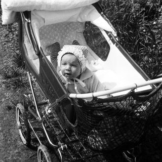 Baby in vintage pram outdoors.