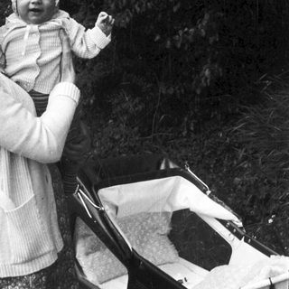 A woman holding a smiling baby outdoors.