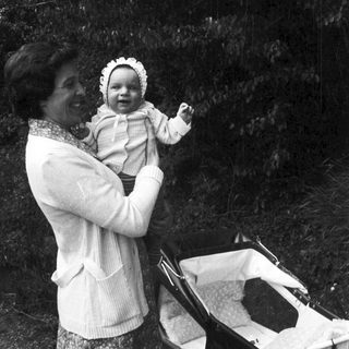 A woman holding a smiling baby outdoors.