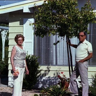 Mid-century couple posing outside modern home.