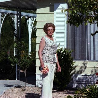 Mid-century couple posing outside modern home.