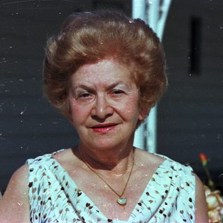 Elderly woman smiling in vintage outdoor photograph.