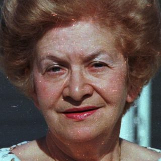 Elderly woman smiling in vintage outdoor photograph.