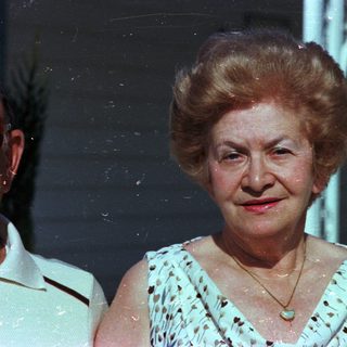 Elderly woman smiling in vintage outdoor photograph.