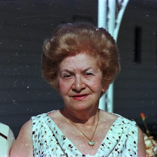 Elderly woman smiling in vintage outdoor photograph.