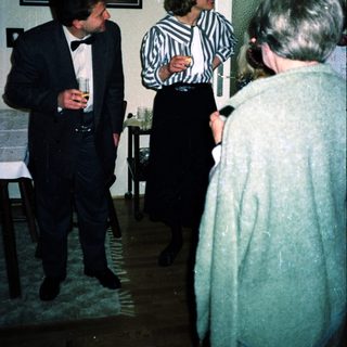 Formal gathering with three people conversing indoors.