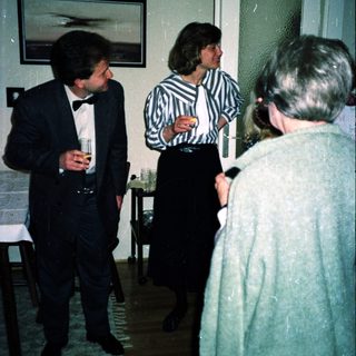 Formal gathering with three people conversing indoors.