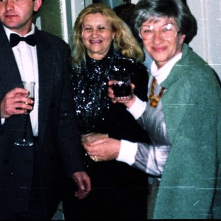 Three adults posing indoors with drinks at an event.