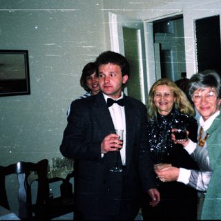 Three adults posing indoors with drinks at an event.