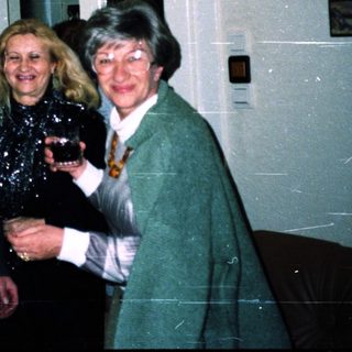 Three adults posing indoors with drinks at an event.