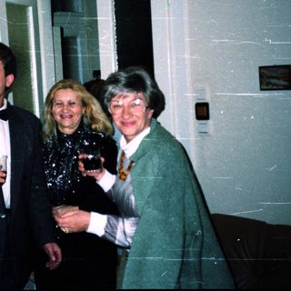 Three adults posing indoors with drinks at an event.