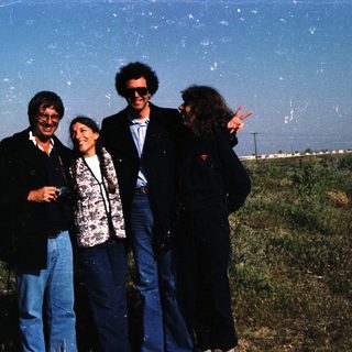 Four people posing outdoors in casual 1980s attire.