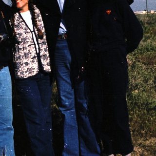 Four people posing outdoors in casual 1980s attire.