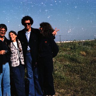 Four people posing outdoors in casual 1980s attire.