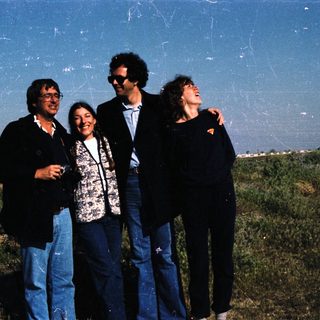 Four people posing outdoors in casual attire.
