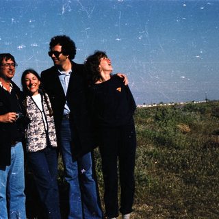 Four people posing outdoors in casual attire.