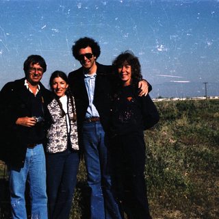 Four people posing outdoors in casual attire.