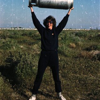 Person holding large gas cylinder outdoors.