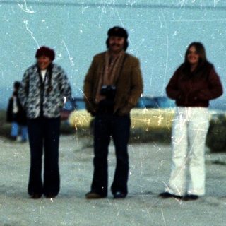 Group of people standing outdoors near a large wall.