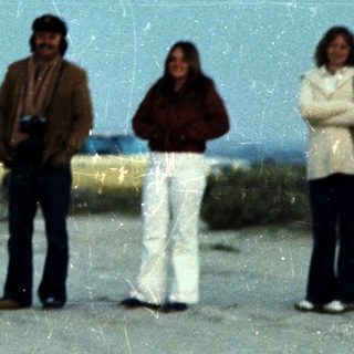 Group of people standing outdoors near a large wall.