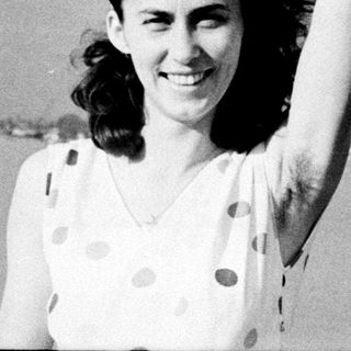 Smiling woman in vintage polka-dot dress by water.