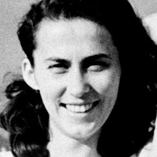 Smiling woman in vintage polka-dot dress by water.