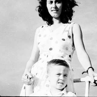 Woman holding young boy on roller skates outdoors.