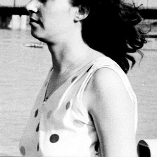 Woman gazes thoughtfully by waterfront pier.