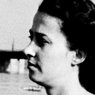 Woman gazes thoughtfully by waterfront pier.
