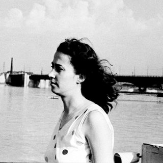 Woman gazes thoughtfully by waterfront pier.