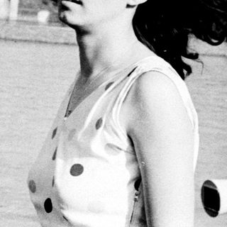 Woman standing by waterfront, windblown hair.