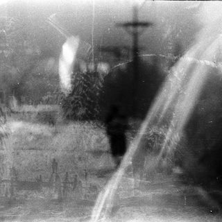 Blurred urban scene with indistinct figures.