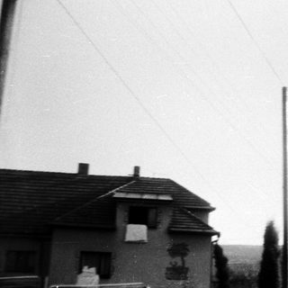 Rural house with chimneys, overcast sky.
