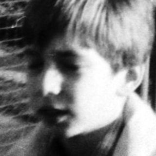 Black-and-white photo of children near a fenced house.