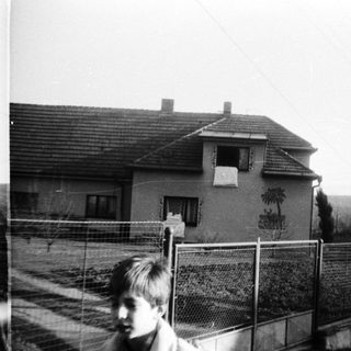 Black-and-white photo of children near a fenced house.