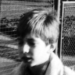 Black-and-white photo of children near a fenced house.