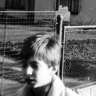 Black-and-white photo of children near a fenced house.