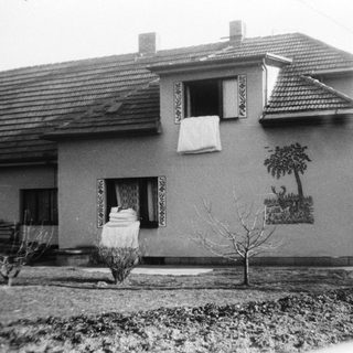 Two-story house with decorative mural, bare trees, and laundry.