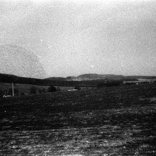 Rural landscape with open fields and distant hills.